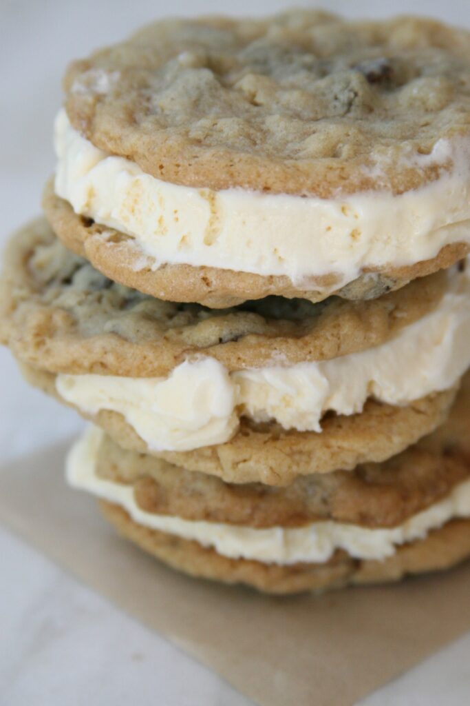 Homemade Cookie Ice Cream Sandwiches with vanilla ice cream stacked on top of each other on a butcher block