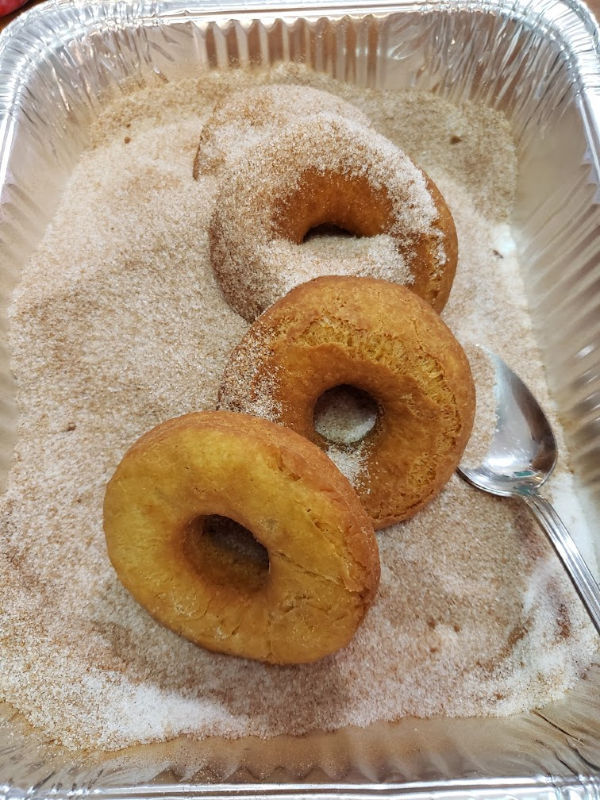 old fashioned doughnuts being rolled in cinnamon sugar mixture