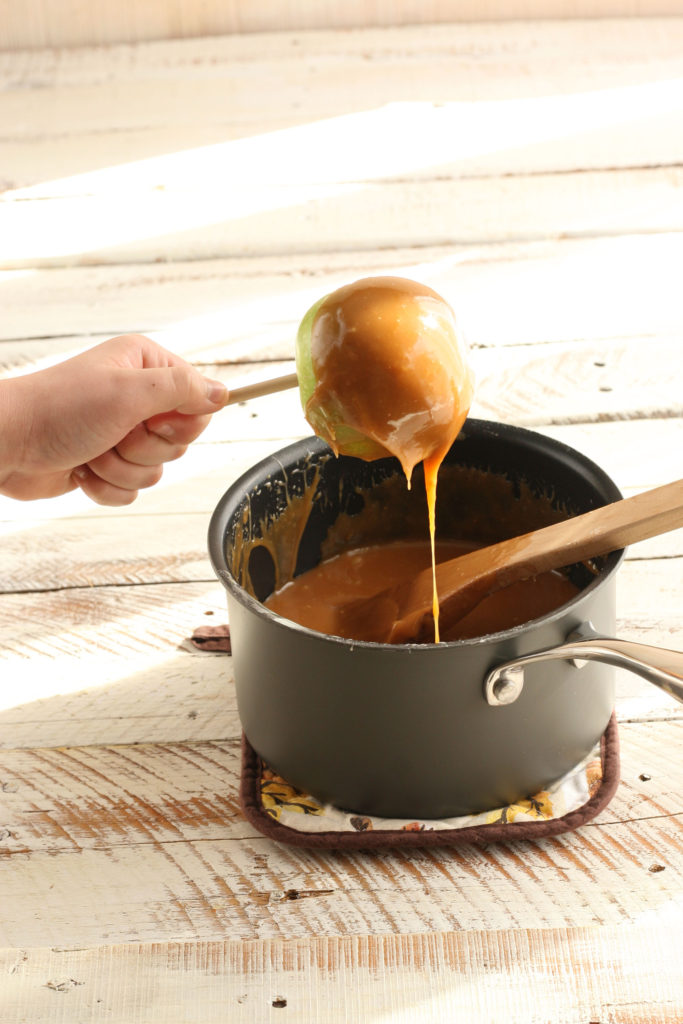 Granny Smith apples dipped into melted caramel in a small saucepan