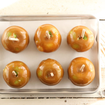 caramel apples cooling on a half sheet pan