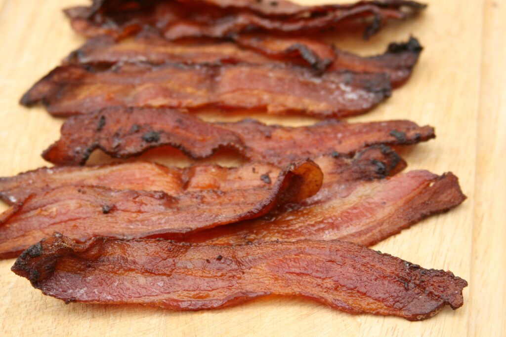 Pieces of maple pepper bacon sitting on wooden cutting board