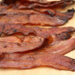 Pieces of maple pepper bacon sitting on wooden cutting board