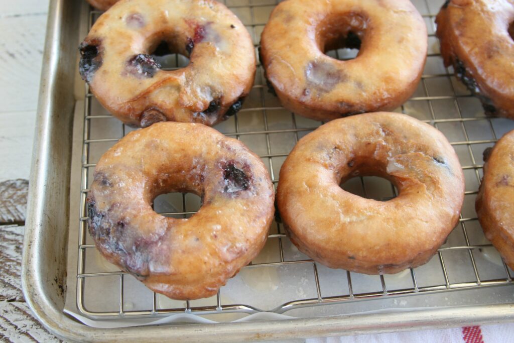 blueberry cake doughnuts with glaze drying on baking rack