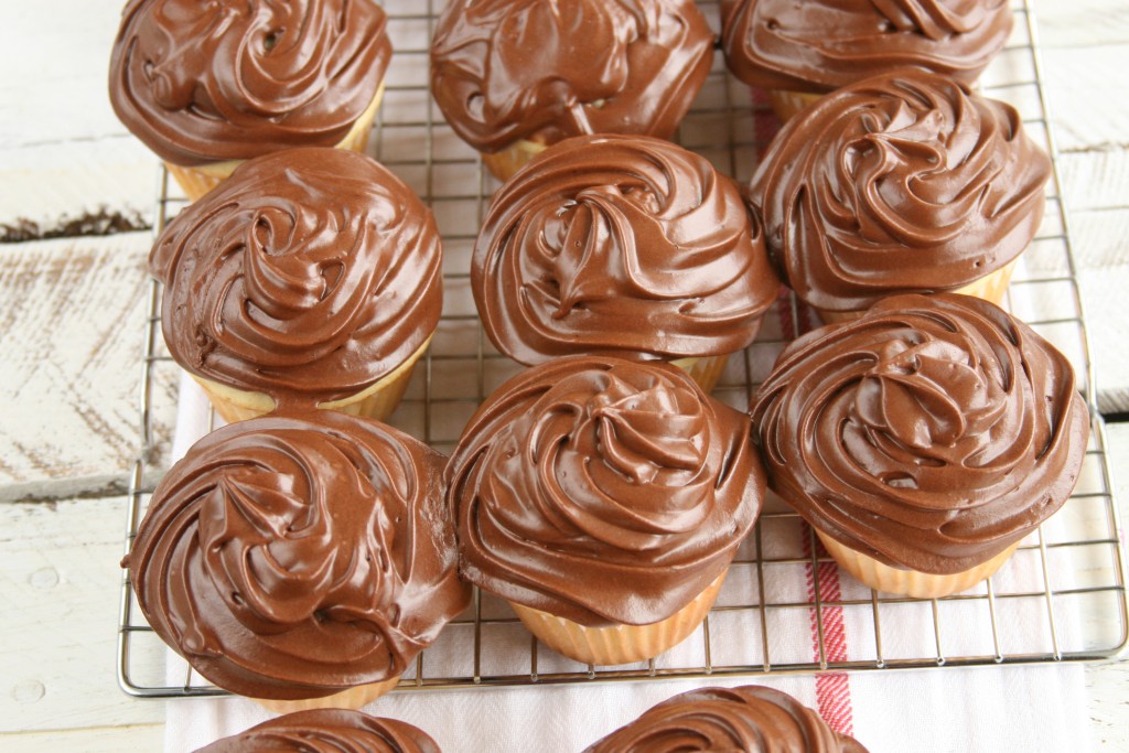 yellow cupcakes with chocolate frosting on a baking rack