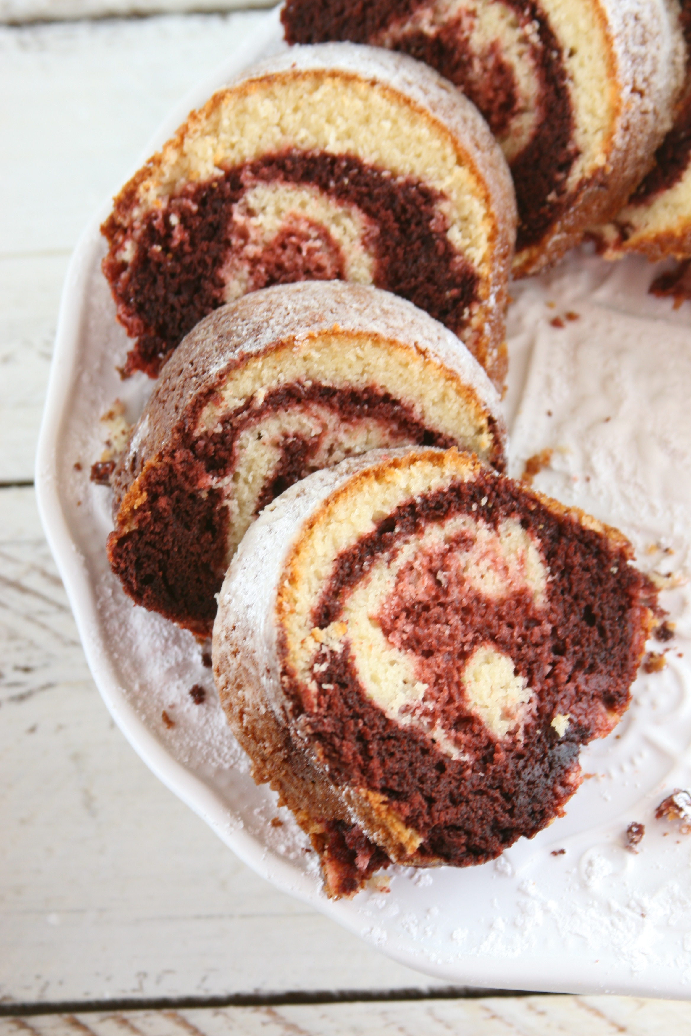Close up of Red velvet marble cake slices on white footed cake dish.