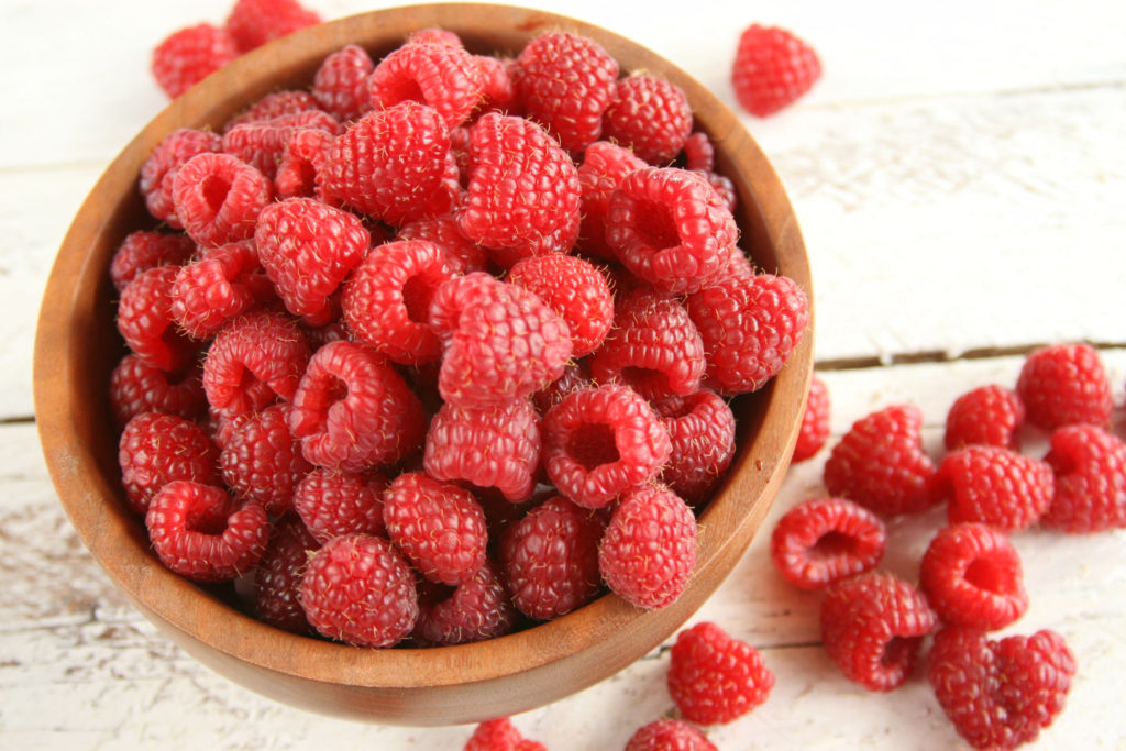 Handmade wooden bowl filled with fresh raspberries