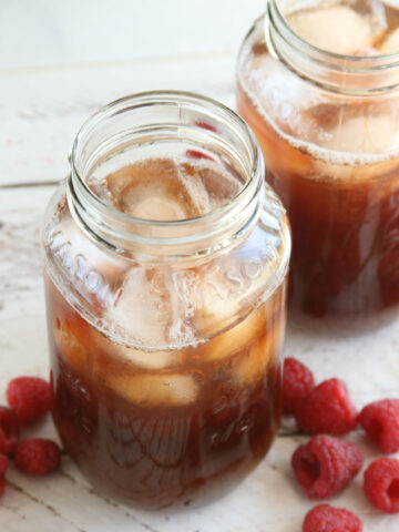 Homemade Raspberry iced tea in glass Mason jars filled with ice cubes