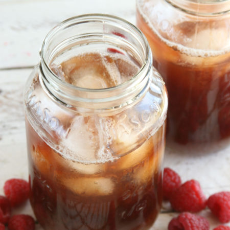 Homemade Raspberry iced tea in glass Mason jars filled with ice cubes