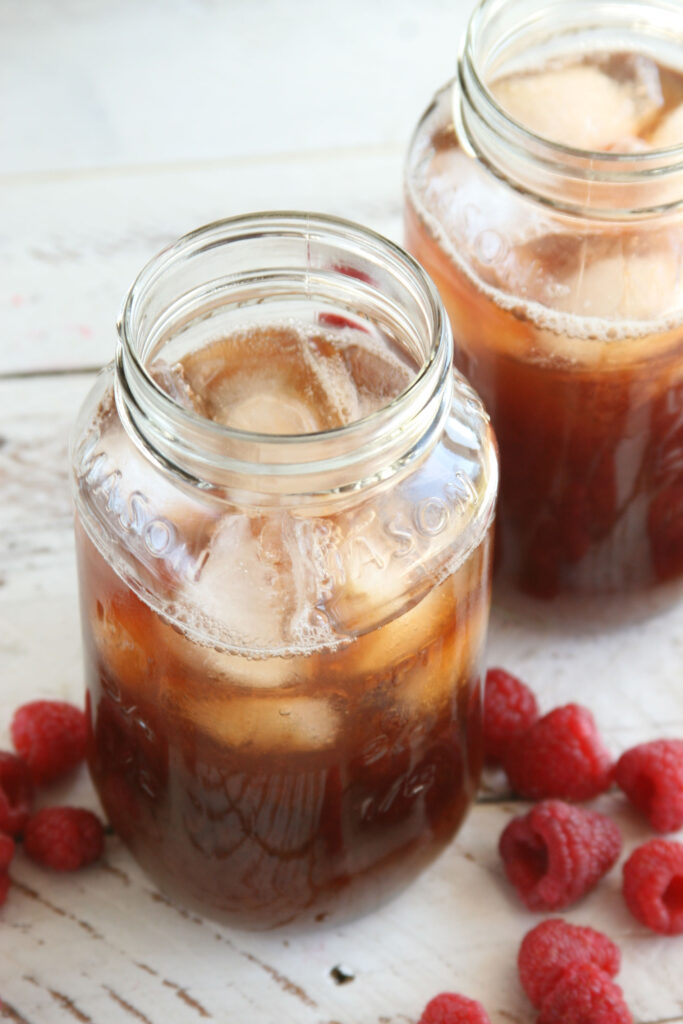 Homemade Raspberry iced tea in glass Mason jars filled with ice cubes