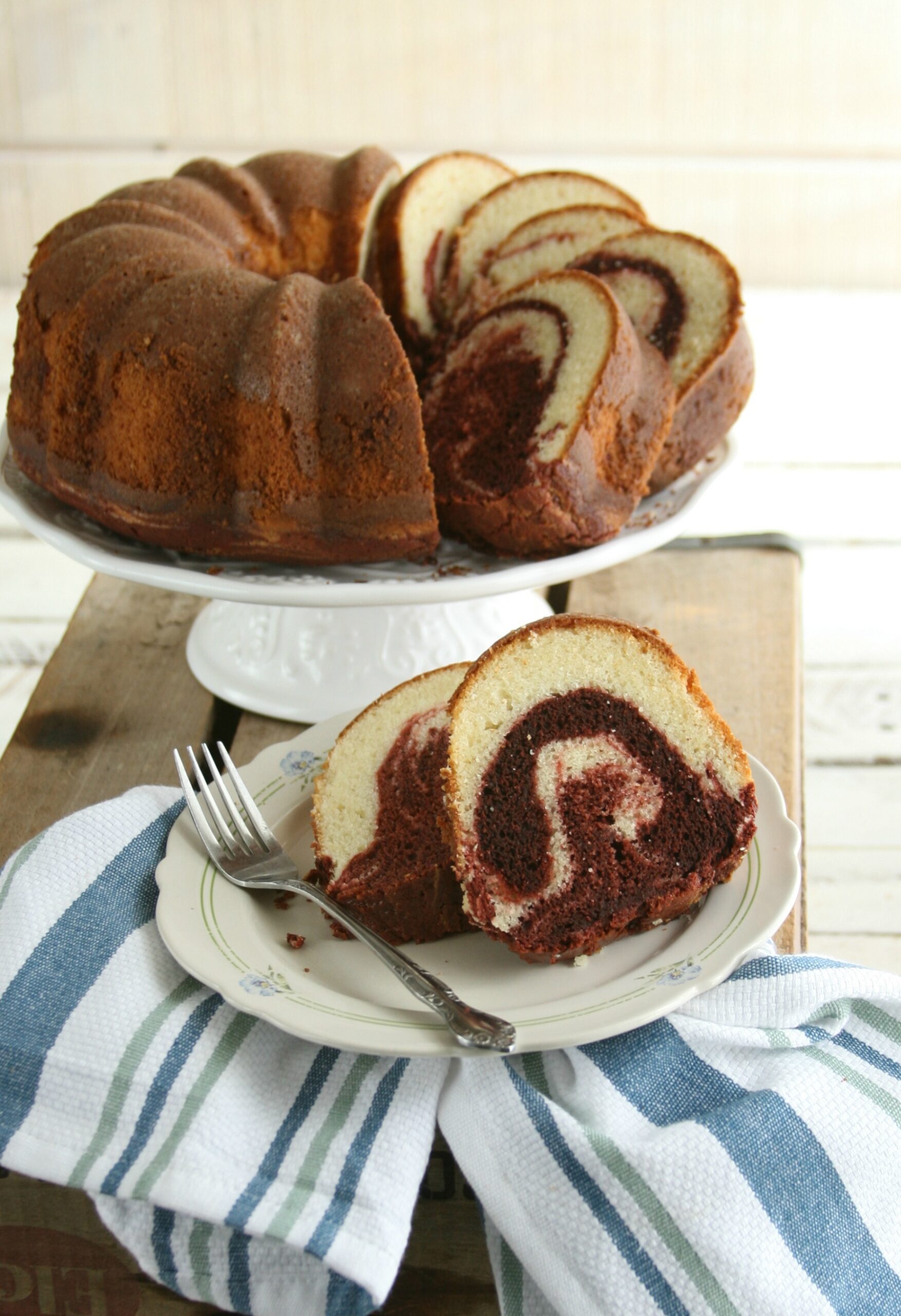 Red velvet marble swirl cake on white footed cake dish.