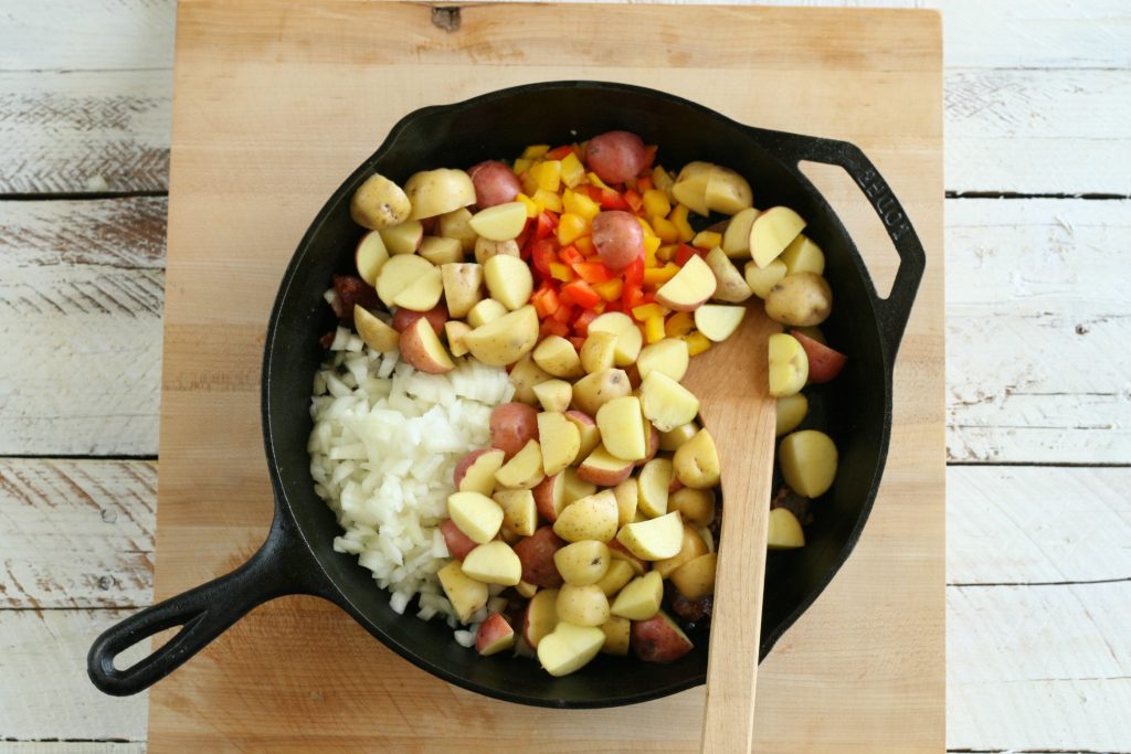 onions, bell peppers, and potatoes in a cast iron skillet