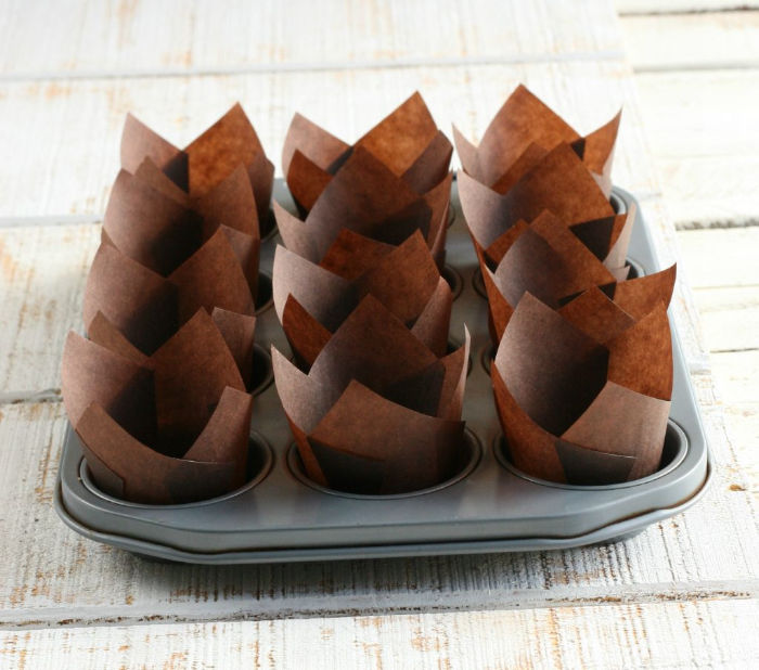 chocolate color tulip shaped paper cupcake liners in a muffin tin