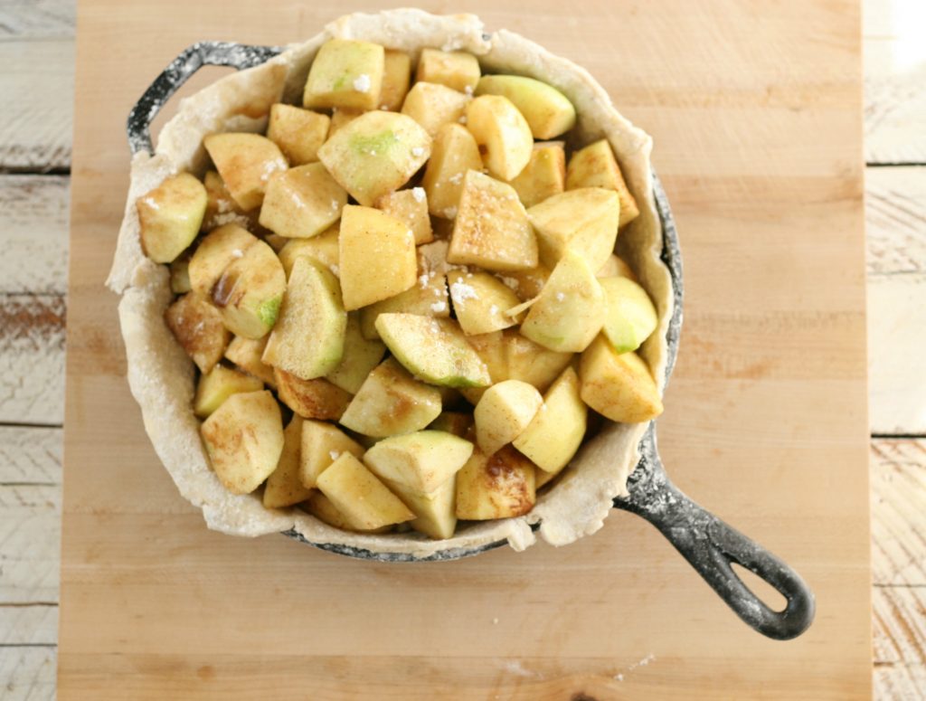 apples piled in a bottom crust in a cast iron skillet