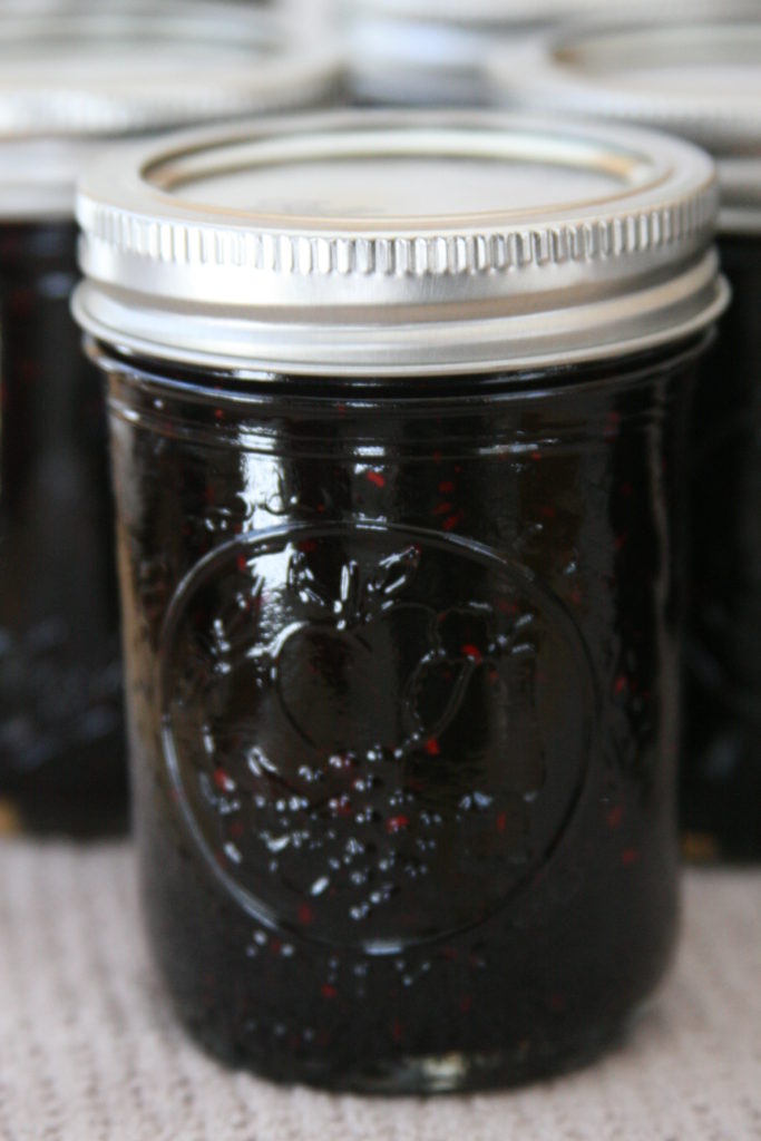 Mixed berry jam in pint mason jars cooling on the counter