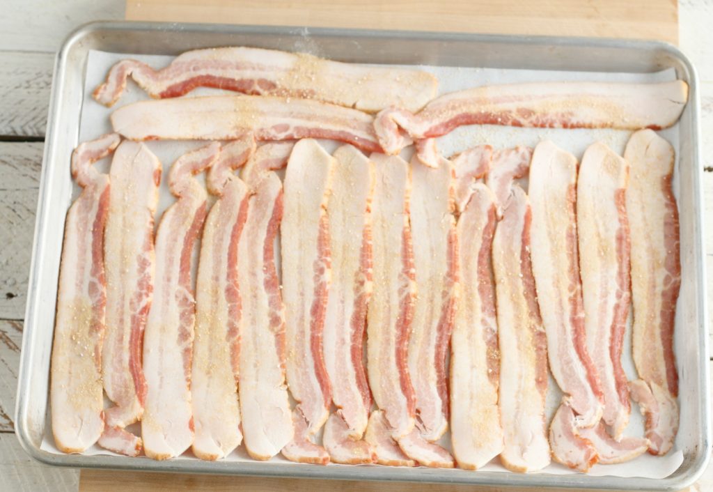 bacon on a half sheet pan sprinkled with granulated maple sugar