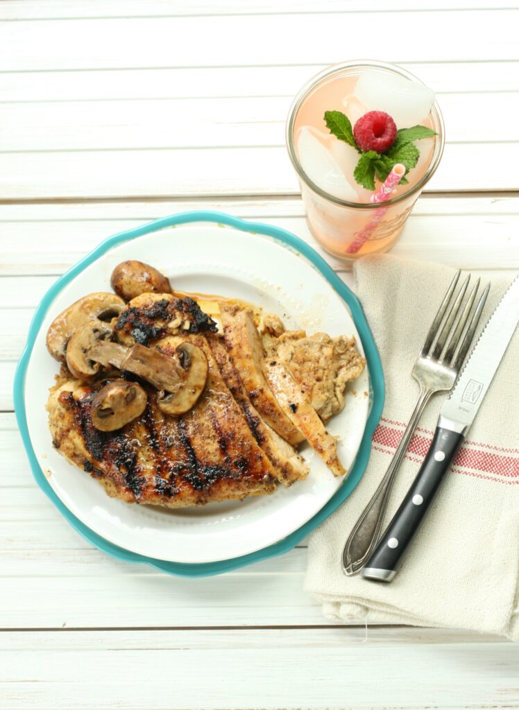 Grilled chicken on a white plate with aqua color rim