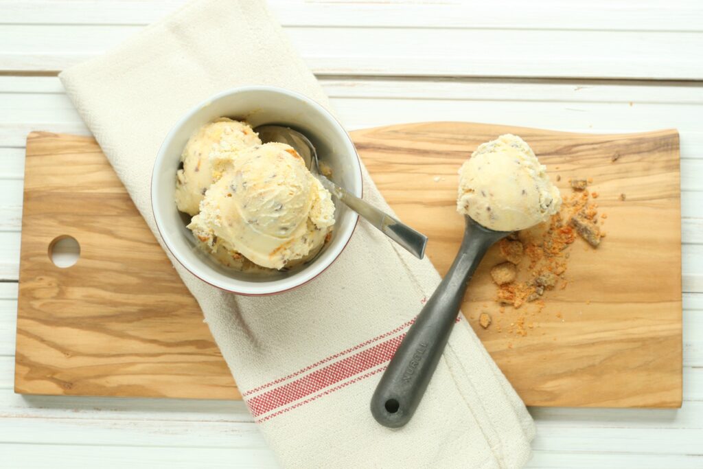 butterfinger ice cream and vintage ice cream scoop sitting on wooden cutting board