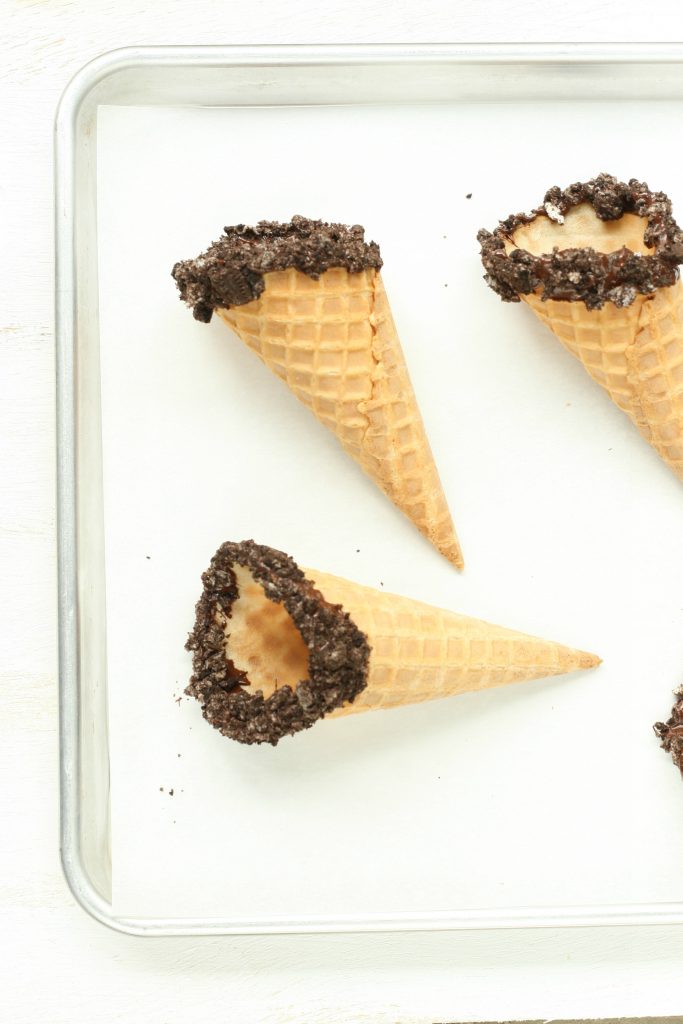 store bought waffle cones with crushed Oreo cookies on edge of cones.