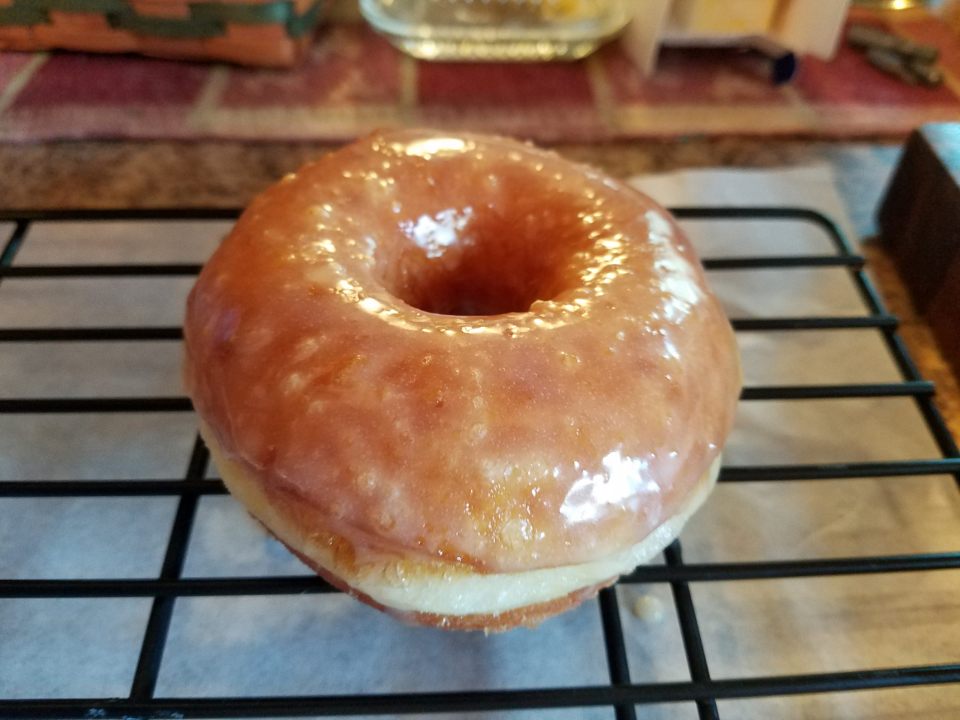 glazed donut drying on a baking rack.