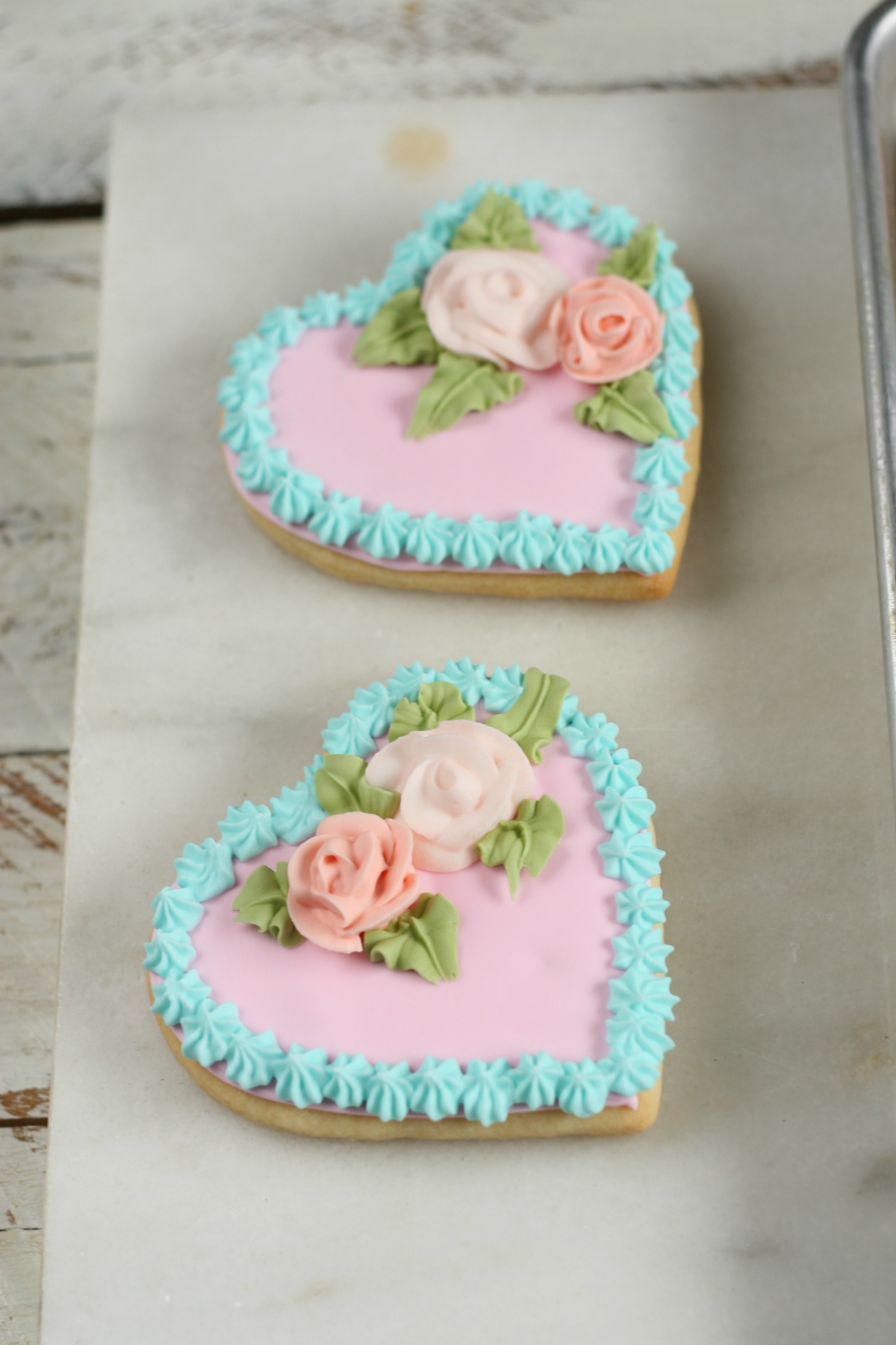Heart sugar cookies with pale pink royal icing and sugar roses