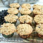 Blueberry muffins cooling on a baking rack with streusel topping