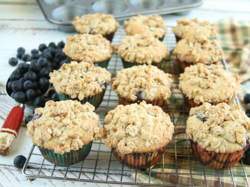 Blueberry muffins cooling on a baking rack with streusel topping