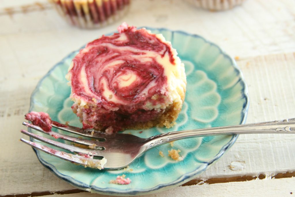 Berry swirl cheesecake on an aqua color floral plate with a fork