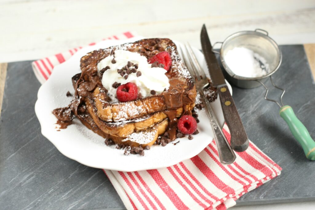 Chocolate Brioche French Toast with mini chocolate chips, whipped cream, and fresh raspberries