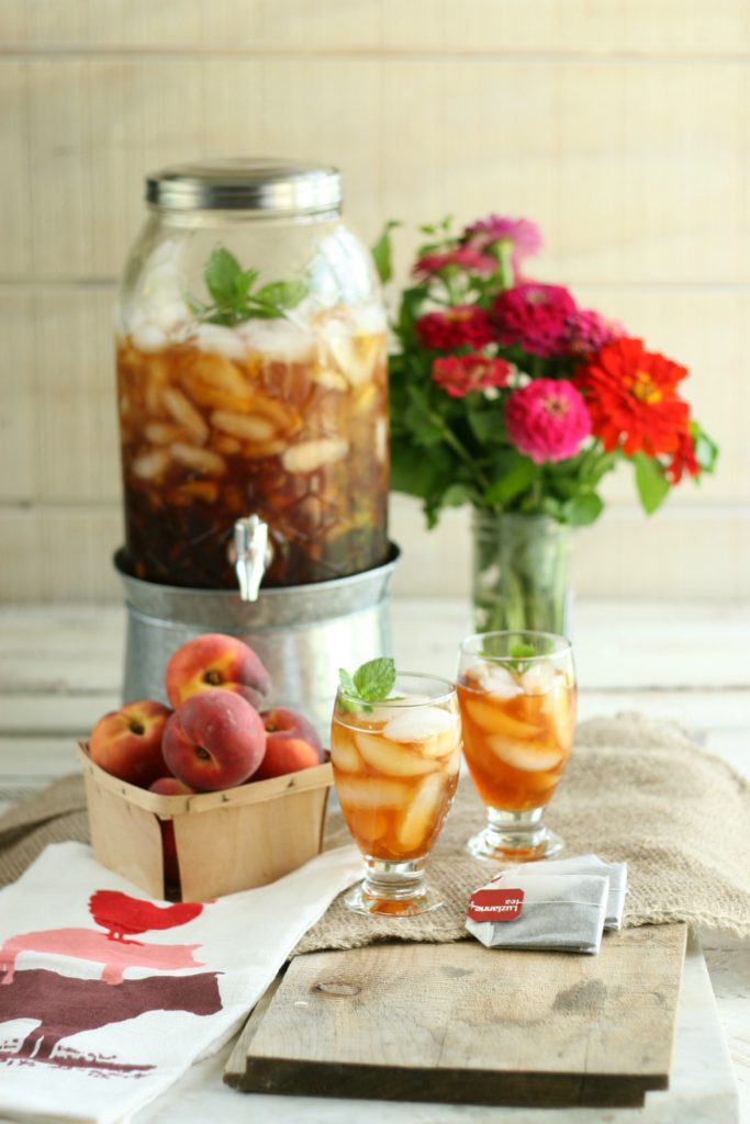 Homemade peach sweet tea in a glass drink dispenser