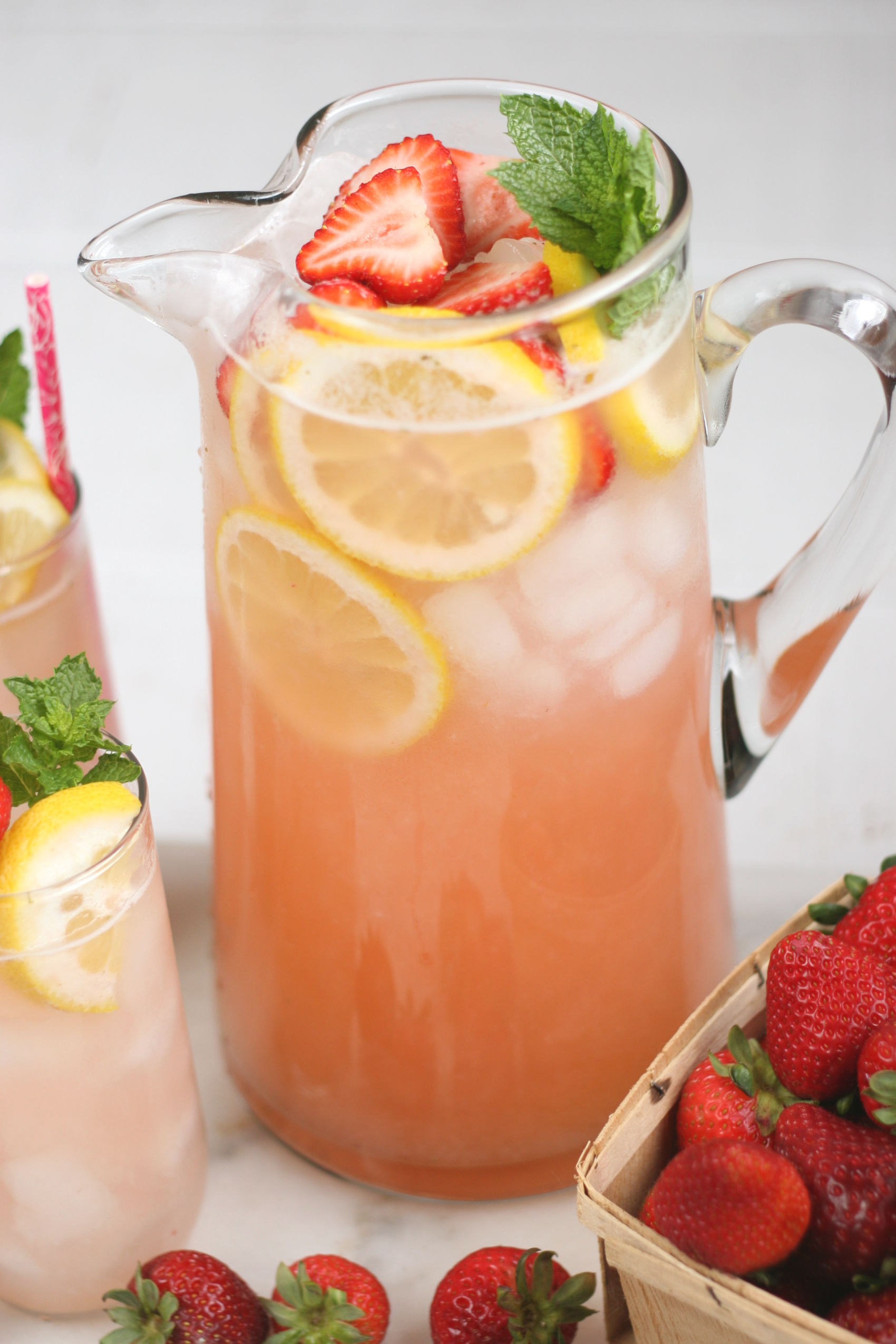 glass pouring pitcher of strawberry lemonade.