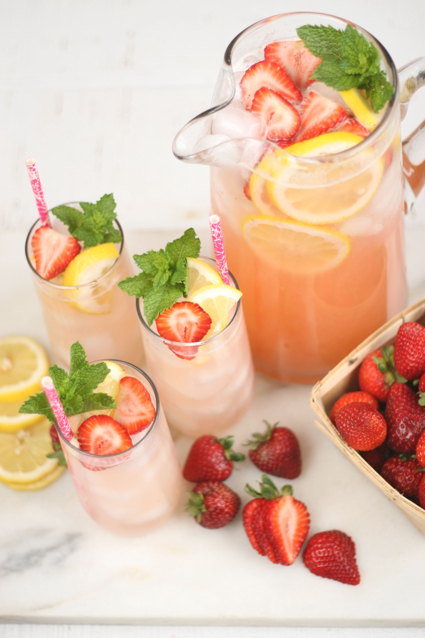 Homemade Lemonade in a glass pouring pitcher with glasses to the side.