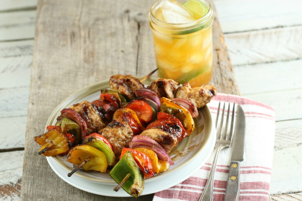 chicken and vegetable kebabs on a plate with fork and knife