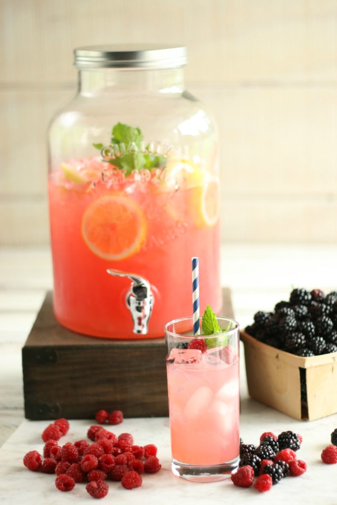 Glass drink dispenser with blackberry raspberry lemonade and glass with paper straw