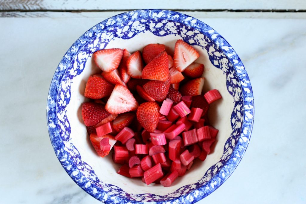 slices of strawberries and rhubarb in a vintage ceramic white bowl with a blue speckled edge