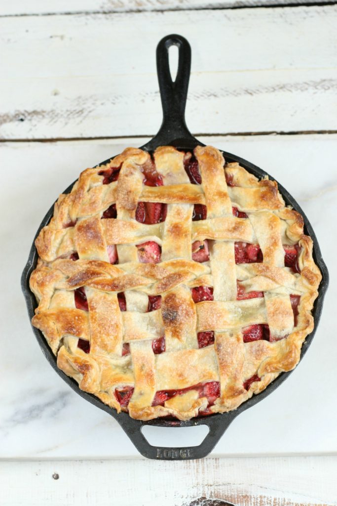 Strawberry rhubarb pie with a golden lattice crust in a cast iron skillet