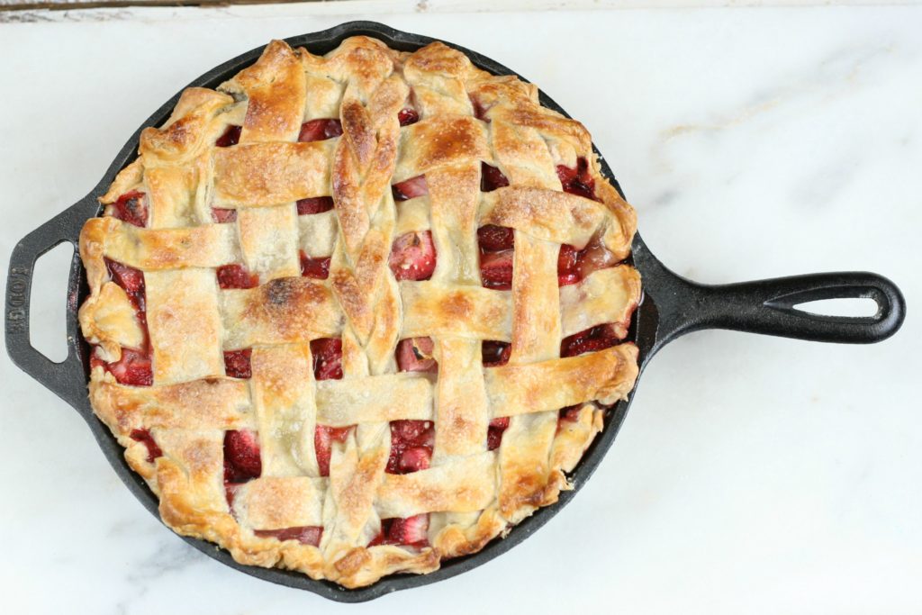 strawberry raspberry rhubarb pie in a cast iron skillet with a lattice crust