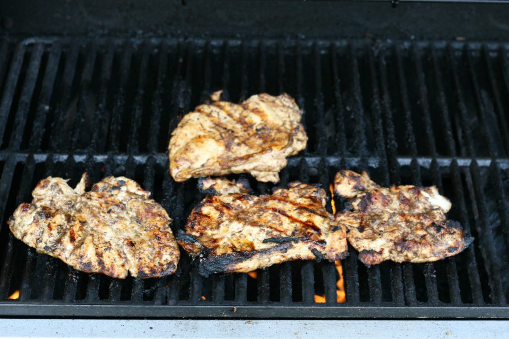 Blood orange and brown sugar boneless skinless chicken breasts cooking on a gas grill.