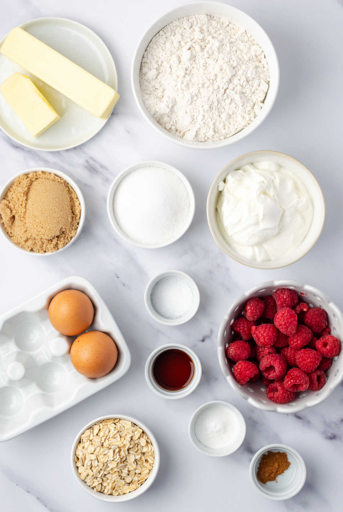 Ingredients for raspberry muffins on white marble.