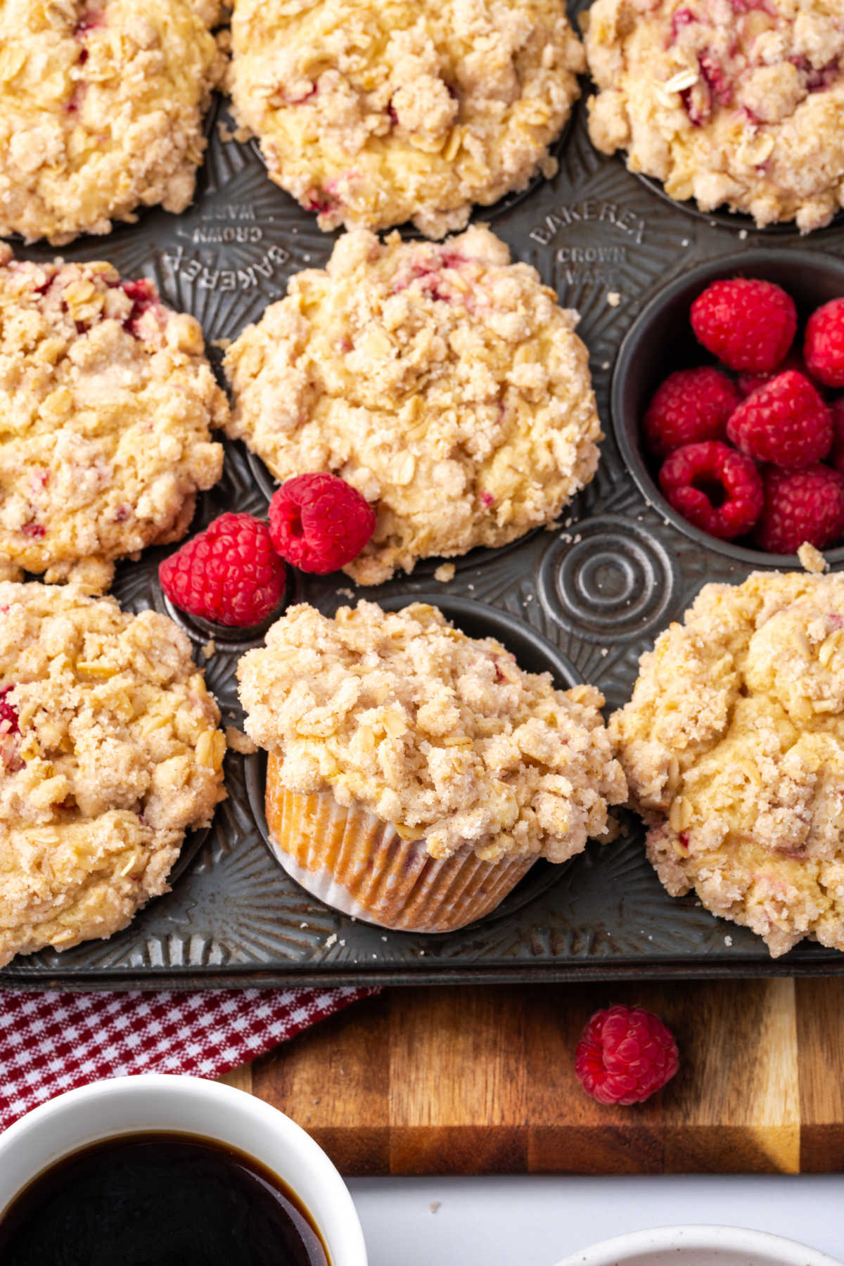 Close up of raspberry crumb muffins in vintage muffin pan with fresh raspberries.