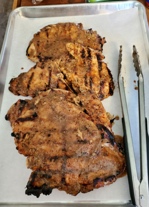 grilled boneless skinless chicken on a half sheet pan lined with parchment paper
