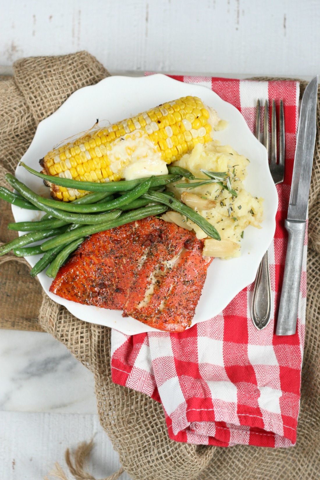 Piece of Wild Salmon with maple bacon spice rub, grilled corn on the cobb, fresh green beans and roasted garlic rosemary mashed potatoes