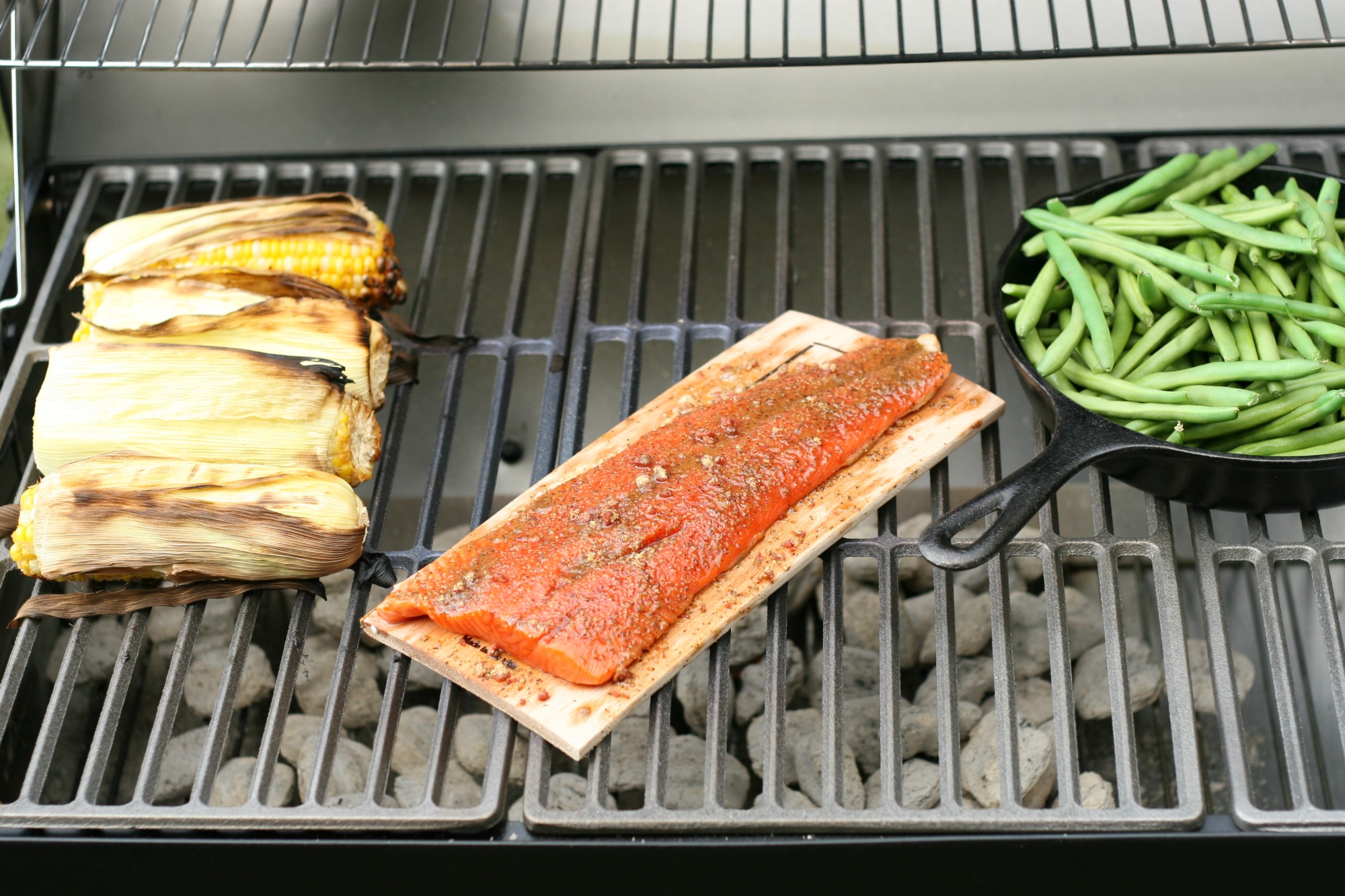 Wild Salmon from The Fresh Market on a maple wood plank on a charcoal grill.
