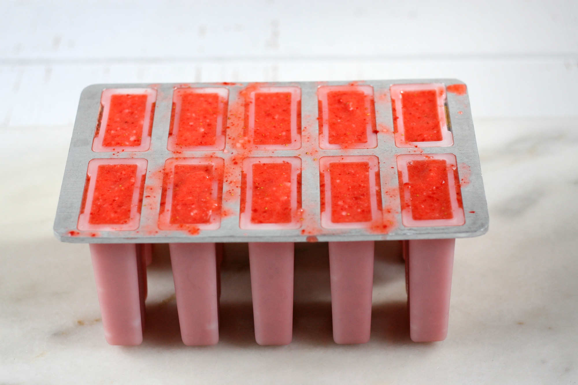 strawberry puree poured into a popsicle mold.