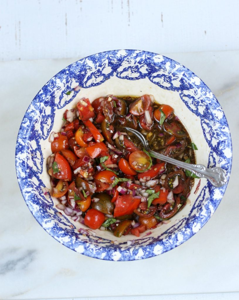 heirloom tomatoes, onions, olive oil, and balsamic vinegar in a blue speckled bowl