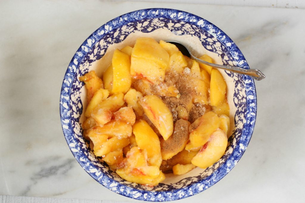 fresh peaches in a blue speckled edge bowl