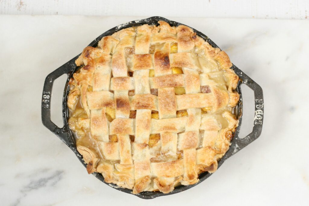 homemade peach pie in 2-handle Lodge cast iron pan