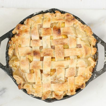 homemade peach pie in 2-handle Lodge cast iron pan