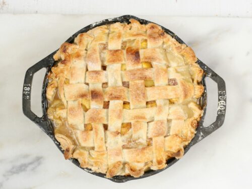 homemade peach pie in 2-handle Lodge cast iron pan