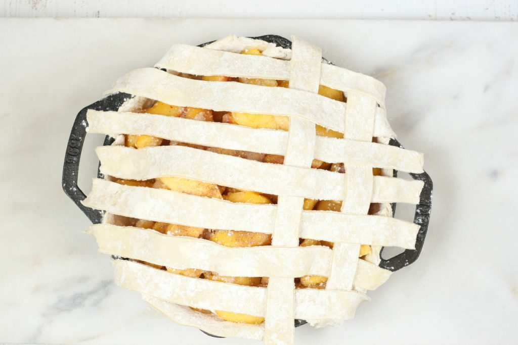 weaving of a lattice crust on a cast iron peach pie