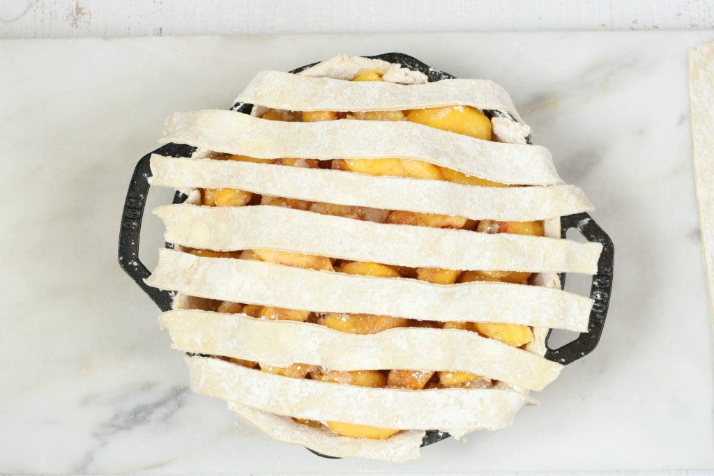 start of a lattice crust on a cast iron peach pie